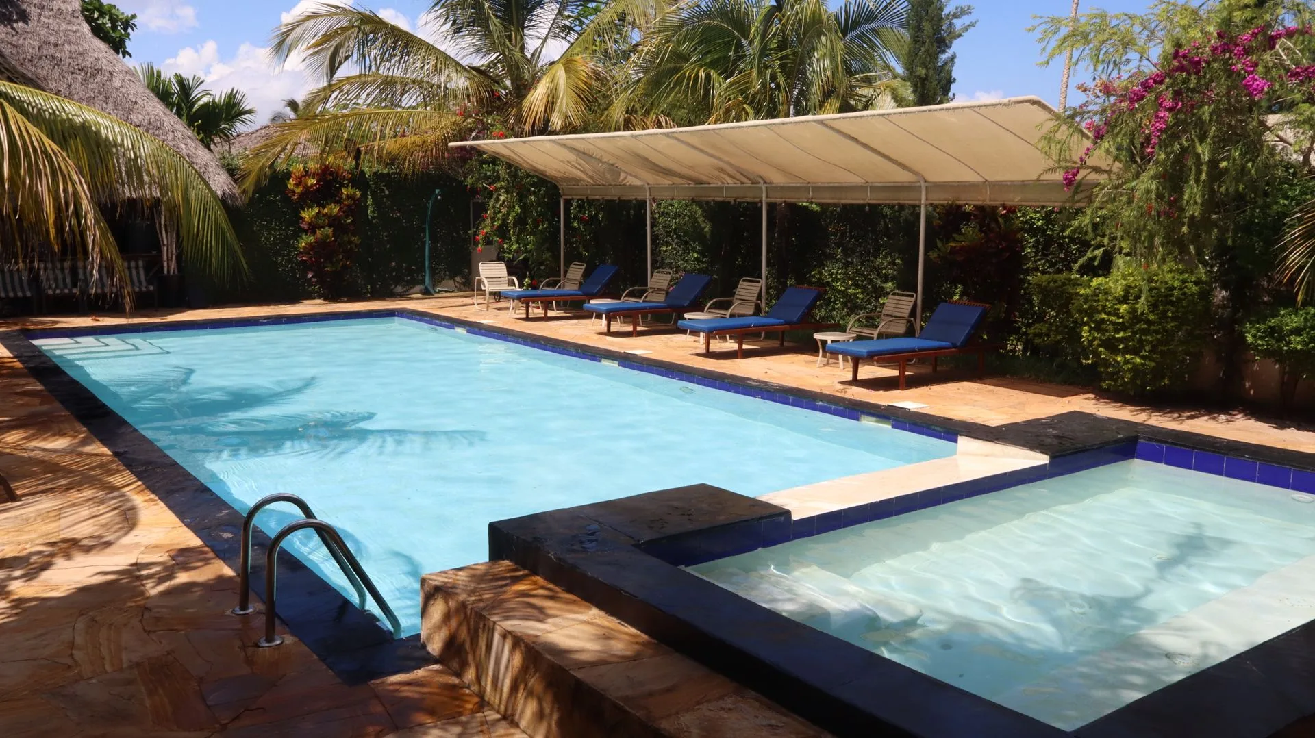 Swimming pool and jacuzzi with deck chairs at Hamia Zanzibar
