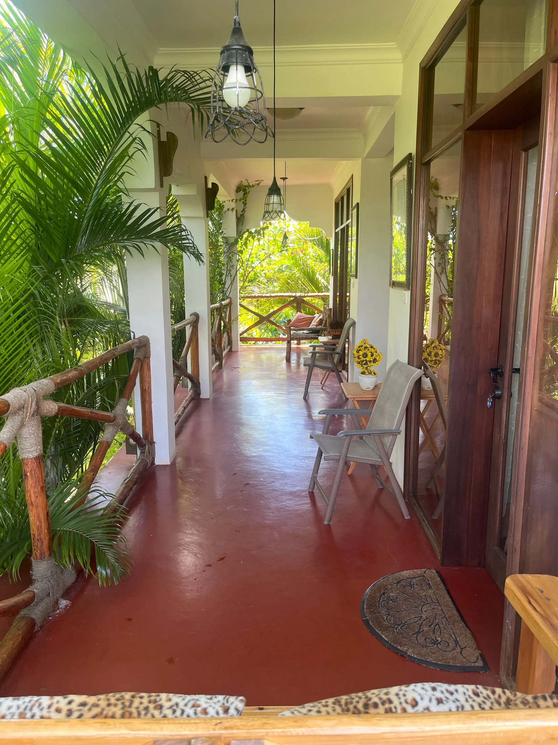 Upper-floor wrap-around balcony at Hamia Zanzibar with polished red floors, lantern lighting and tropical views